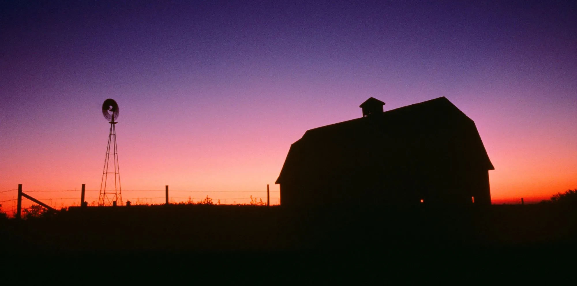 Silhouette of a barn at sunset